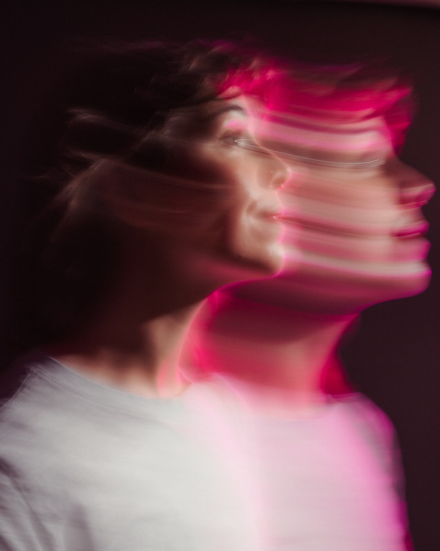 Josaleigh Pollett photographed in profile in a white t-shirt, the image blurred by motion in pink light